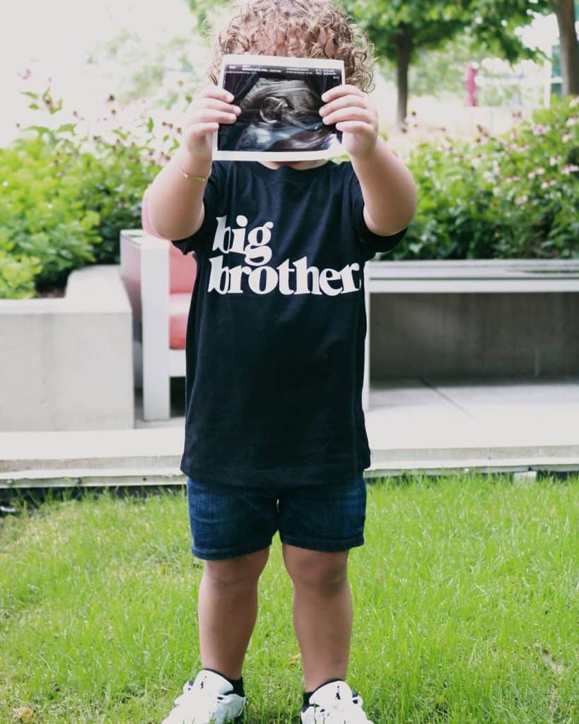 Javier's son holding a picture of his new baby brother