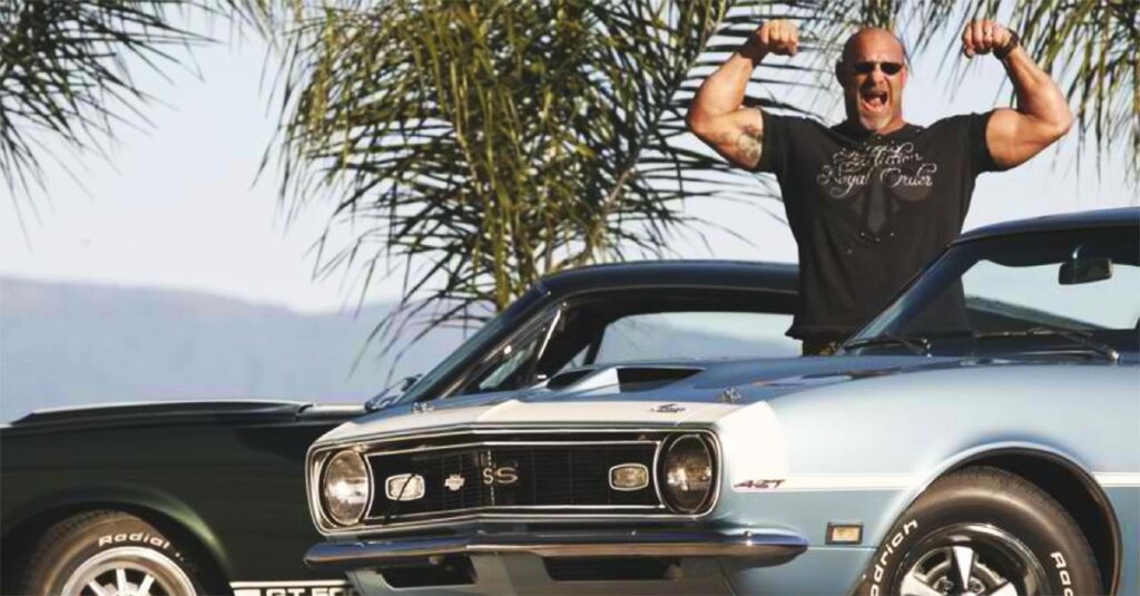 Bill Goldberg posing with one of his vintage cars