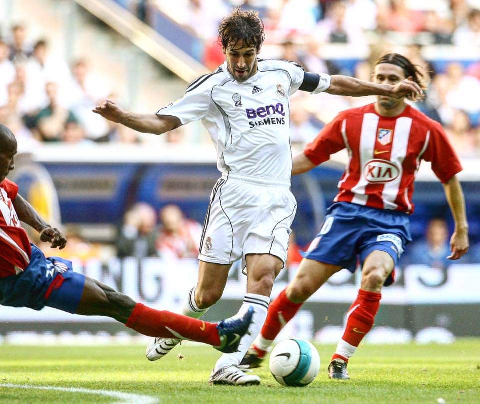 Raul Gonzalez tries to dribble past Atletico Madrid defenders